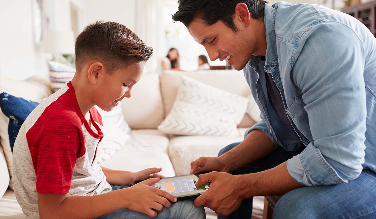 Padre latino mostrando a su hijo cómo navegar en su tableta